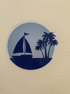 Silhoutte of Sailboat and several palm trees against light blue background. 